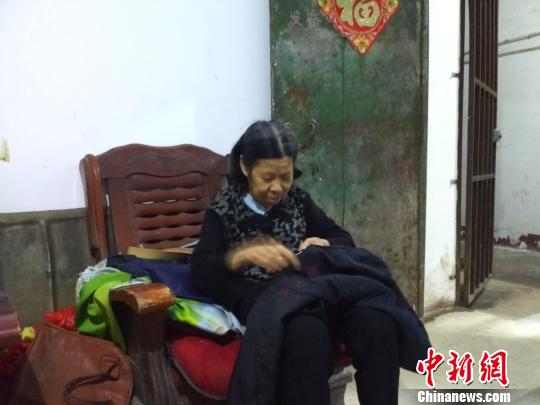 李新彩老人给张满英缝补衣服。　谢丽萍 摄
